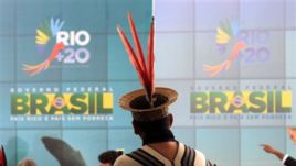 An Ashanink indigenous man stands before a poster promoting the launch of the Rio + 20 sustainable development conference in Rio, Brazil