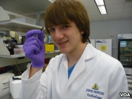 Jack Andraka, 16, with his pancreatic cancer sensor strip at the Johns Hopkins lab in Baltimore. (VOA/J. Taboh)