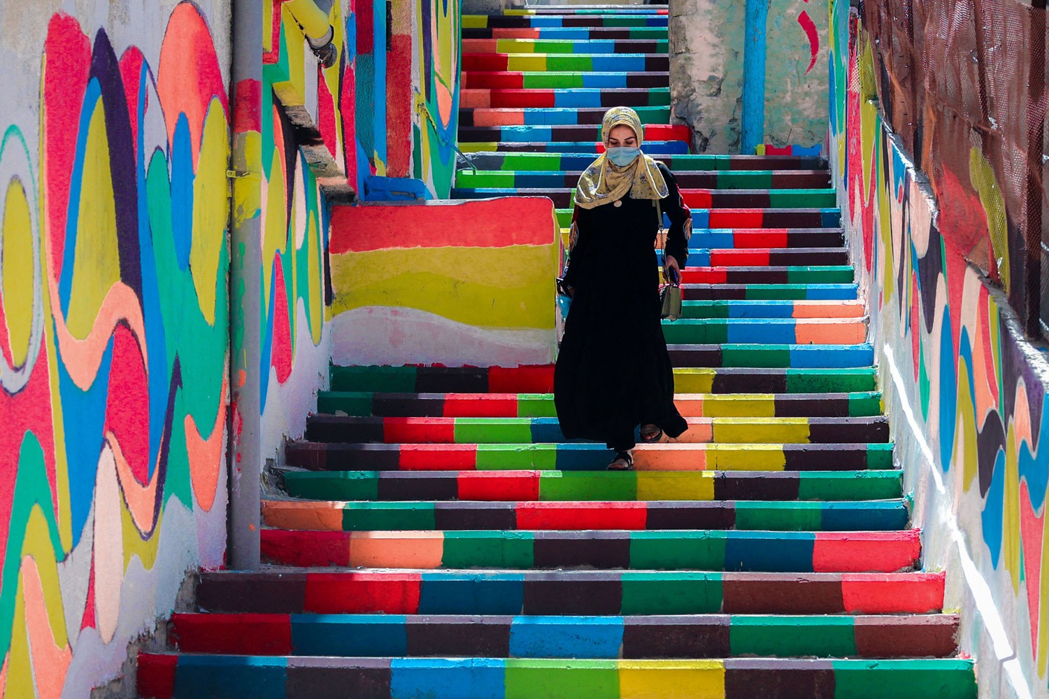 A woman walks down steps decorated with vibrant colors.